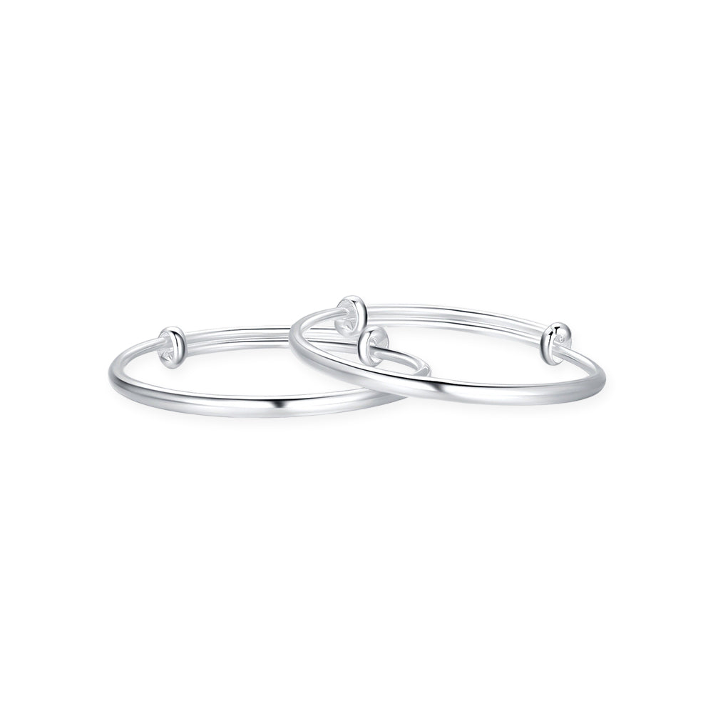 ChowTaiSeng 990 pure silver baby bangles side view on white background — two slim adjustable bangles stacked together showing the sliding wire mechanism and rounded cross-section profile