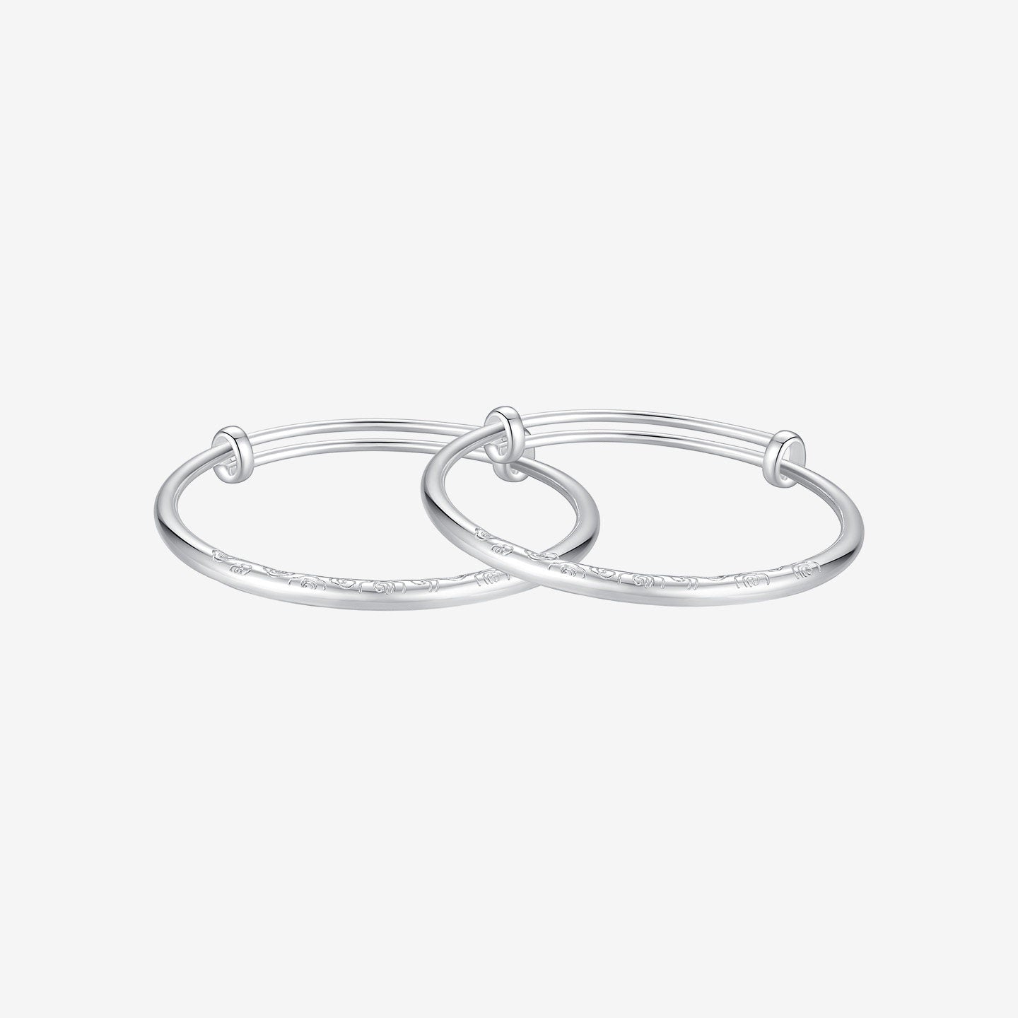 ChowTaiSeng 990 pure silver auspicious cloud baby bangles side view on white background — two adjustable bangles stacked together showing the engraved cloud pattern along the lower band and sliding-knot closure mechanism