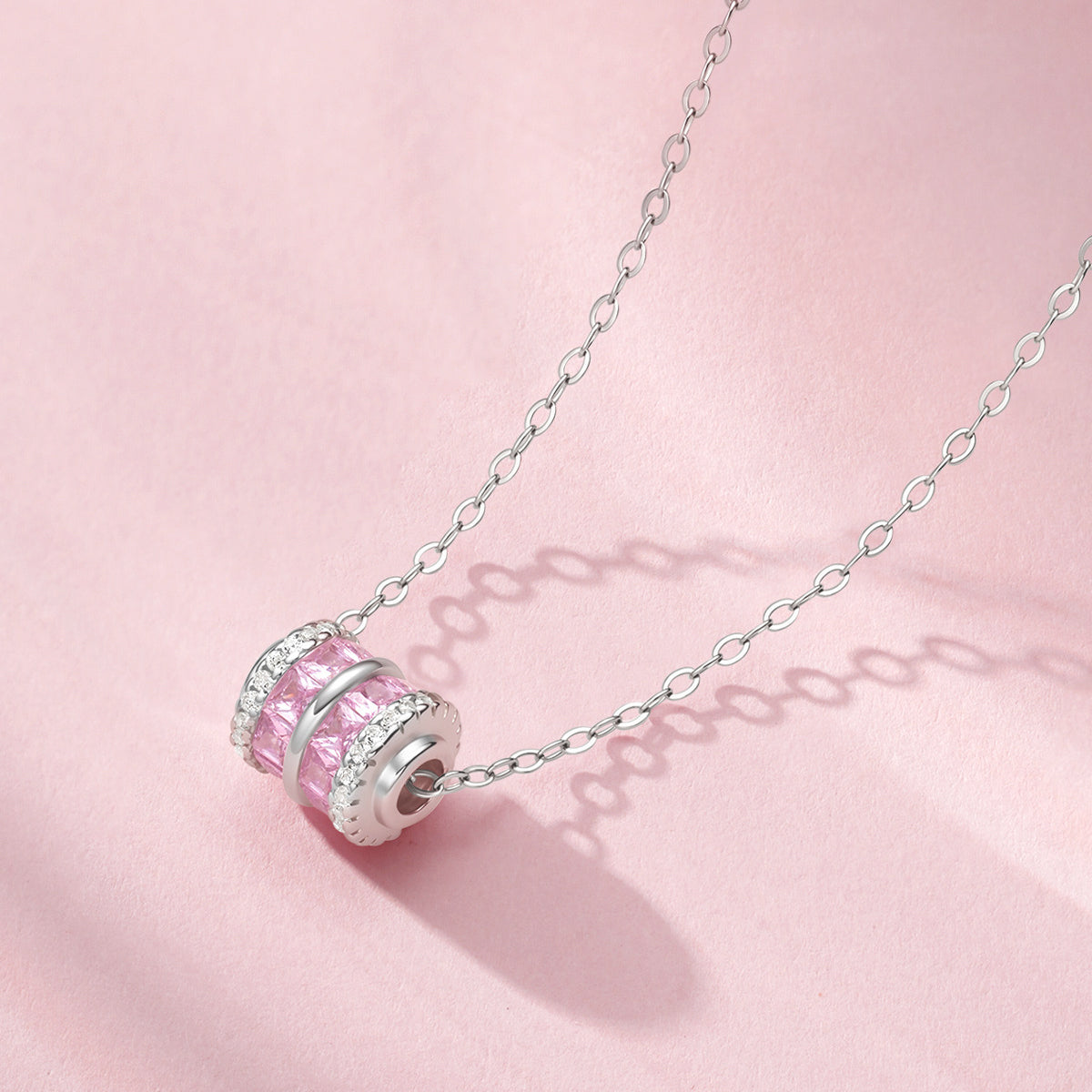 ChowTaiSeng S0N301368CH 925 sterling silver pink zircon small waist barrel pendant close-up on pink background — princess-cut pink cubic zirconia center with white CZ pave rims, silver cable chain threading through pendant