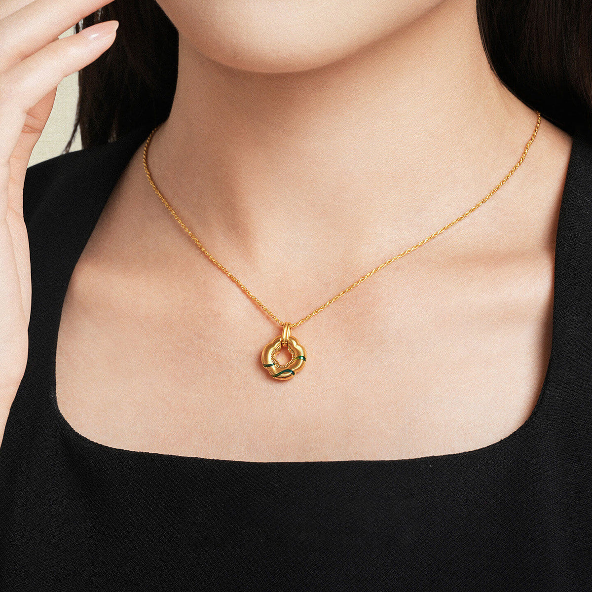 Model wearing ChowTaiSeng 24K Gold Green Clover Pendant on gold chain, black top, front view
