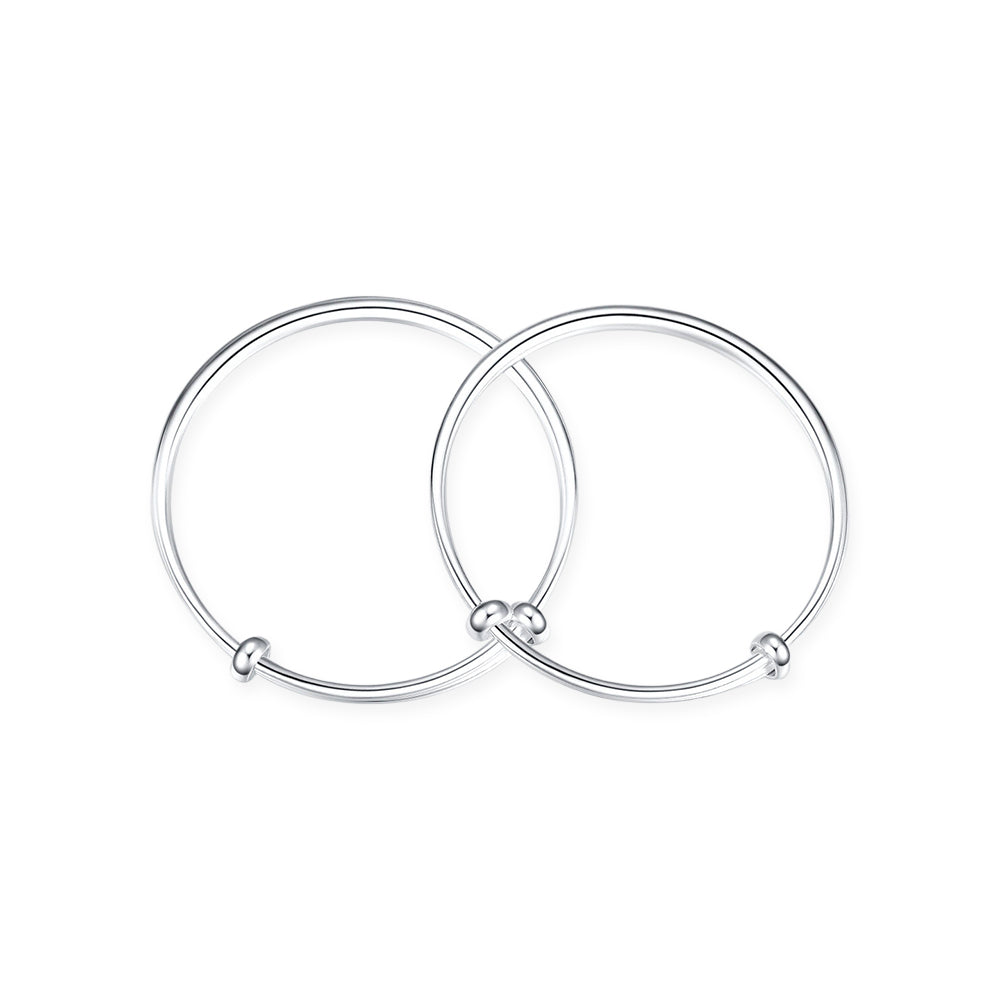 ChowTaiSeng 990 pure silver baby bangles front view on white background — two adjustable bangles overlapping in a circular arrangement, showing the clean smooth surface and sliding knot closure at bottom