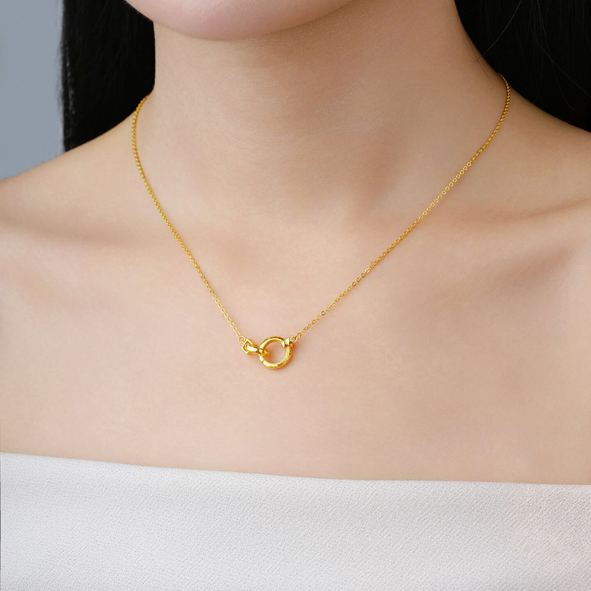 Gold-plated silver double-circle necklace resting at a model's neckline above a white top