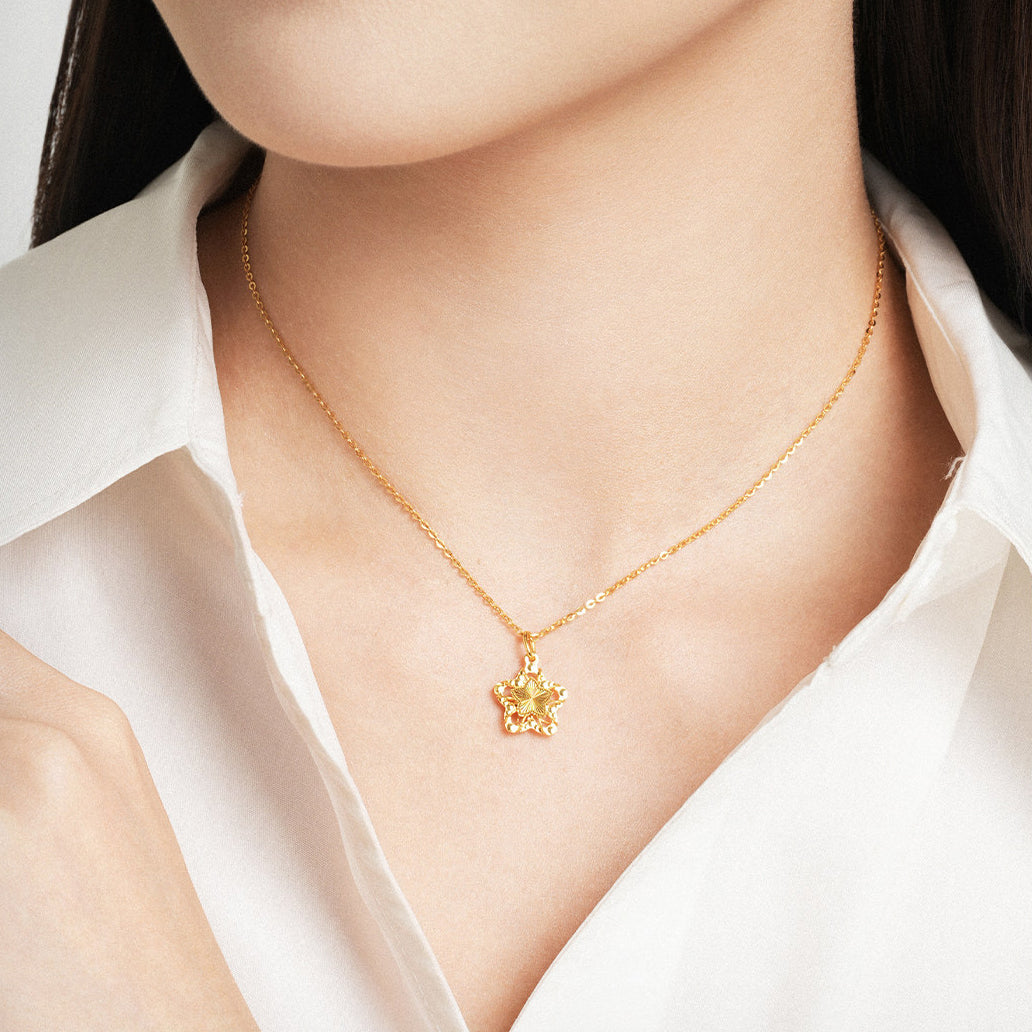 Model wearing ChowTaiSeng 24K gold wishing star pendant necklace — neckline close-up, hollow filigree gold star pendant on cable chain, white shirt, light background