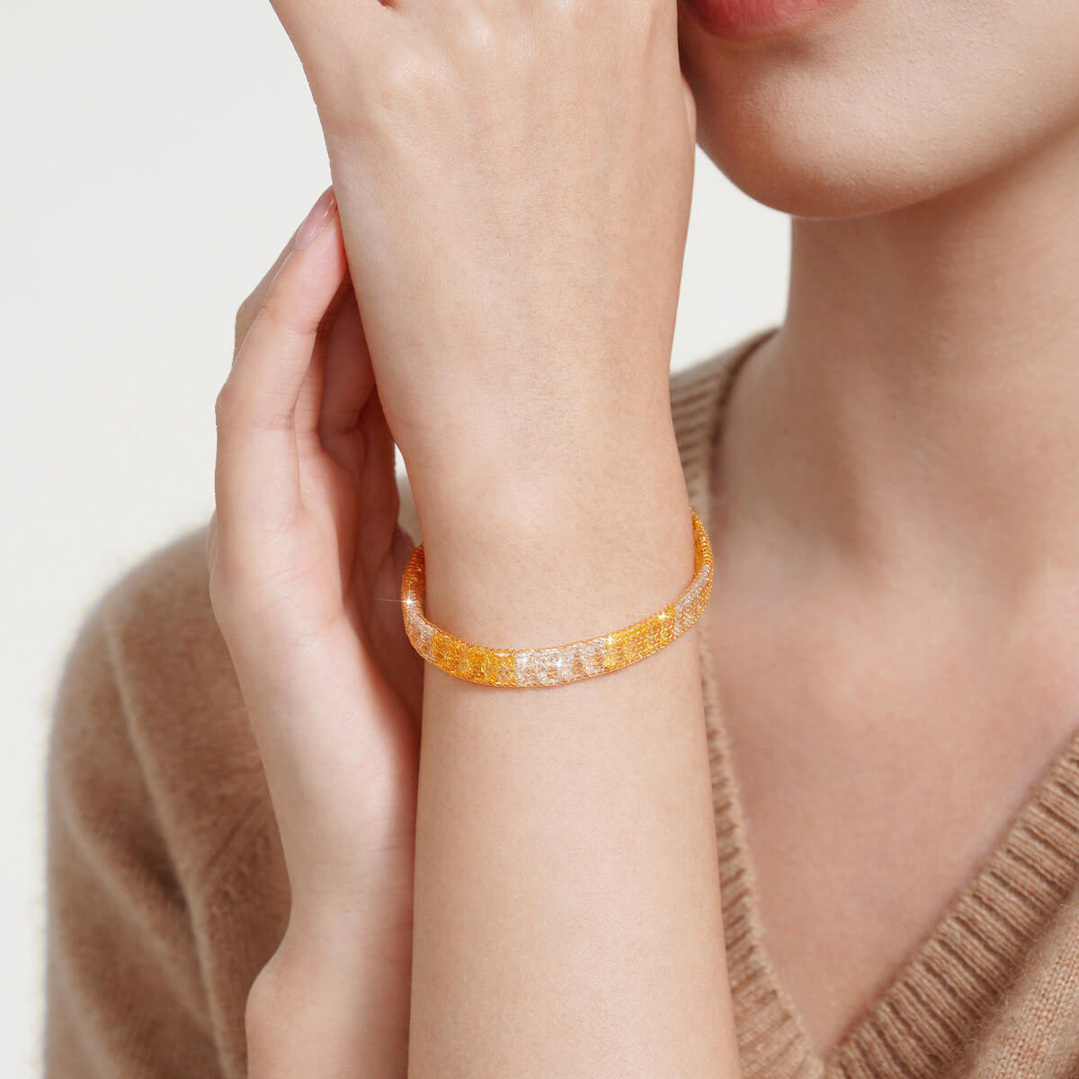 Two-tone gold-plated silver mesh bracelet with cubic zirconia on a model's wrist beside a beige knit top