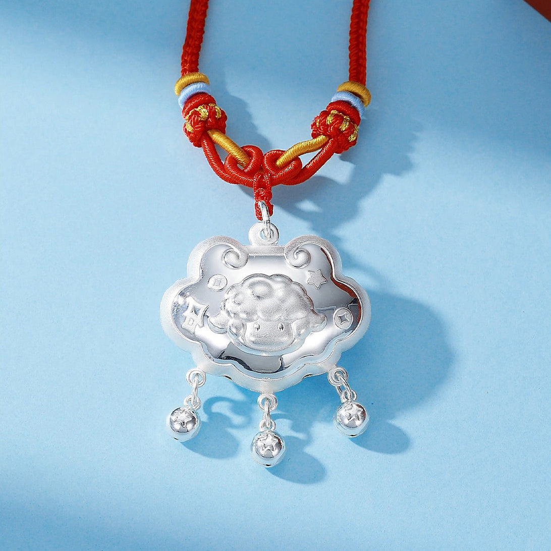 990 pure silver peace sheep Ruyi lock pendant close-up on blue background — cloud-shaped lock with embossed sheep face, three star-engraved silver bell dangles, red and gold braided cord