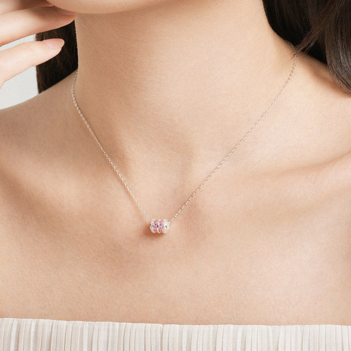 Asian model wearing ChowTaiSeng S0N301368CH silver pink zircon small waist barrel necklace on silver cable chain, pendant centered at collarbone, white strapless top background