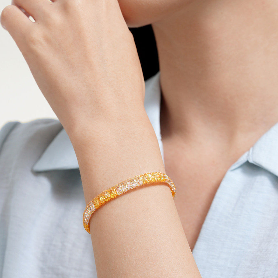 Model wearing a two-tone gold-plated silver mesh bracelet with cubic zirconia and a light blue shirt