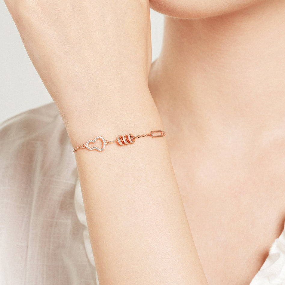 ChowTaiSeng sterling silver gourd bracelet with cubic zirconia worn on raised wrist, side view