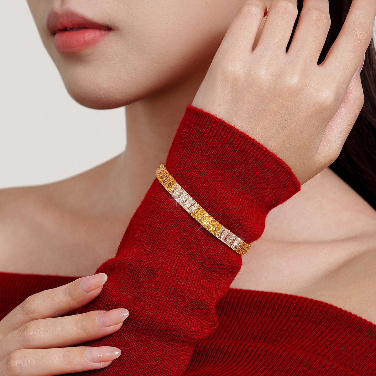 Model wearing a two-tone gold-plated silver mesh bracelet with cubic zirconia over a red sweater sleeve