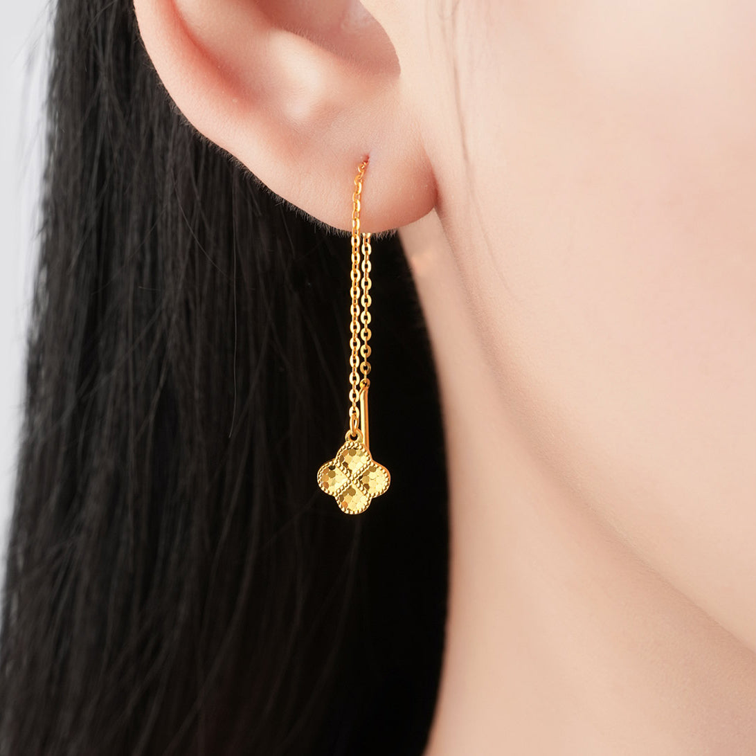 Close-up of a model wearing a gold-tone clover threader earring with a fine chain and faceted charm