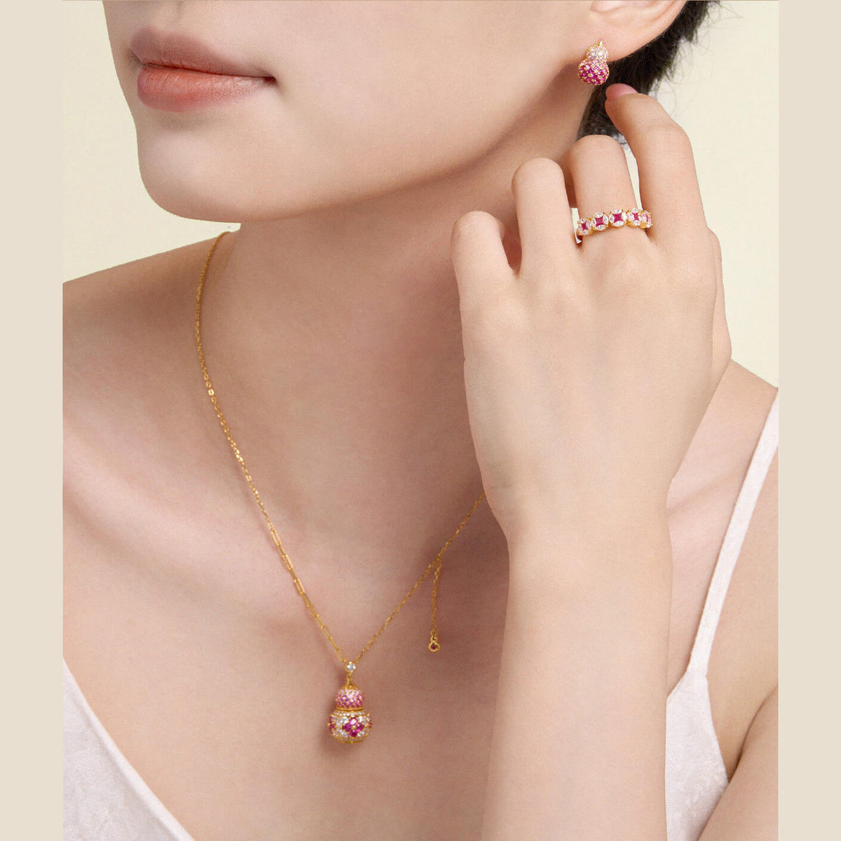 Model wearing a gold-plated silver pink gourd necklace and matching stud earrings with a white top