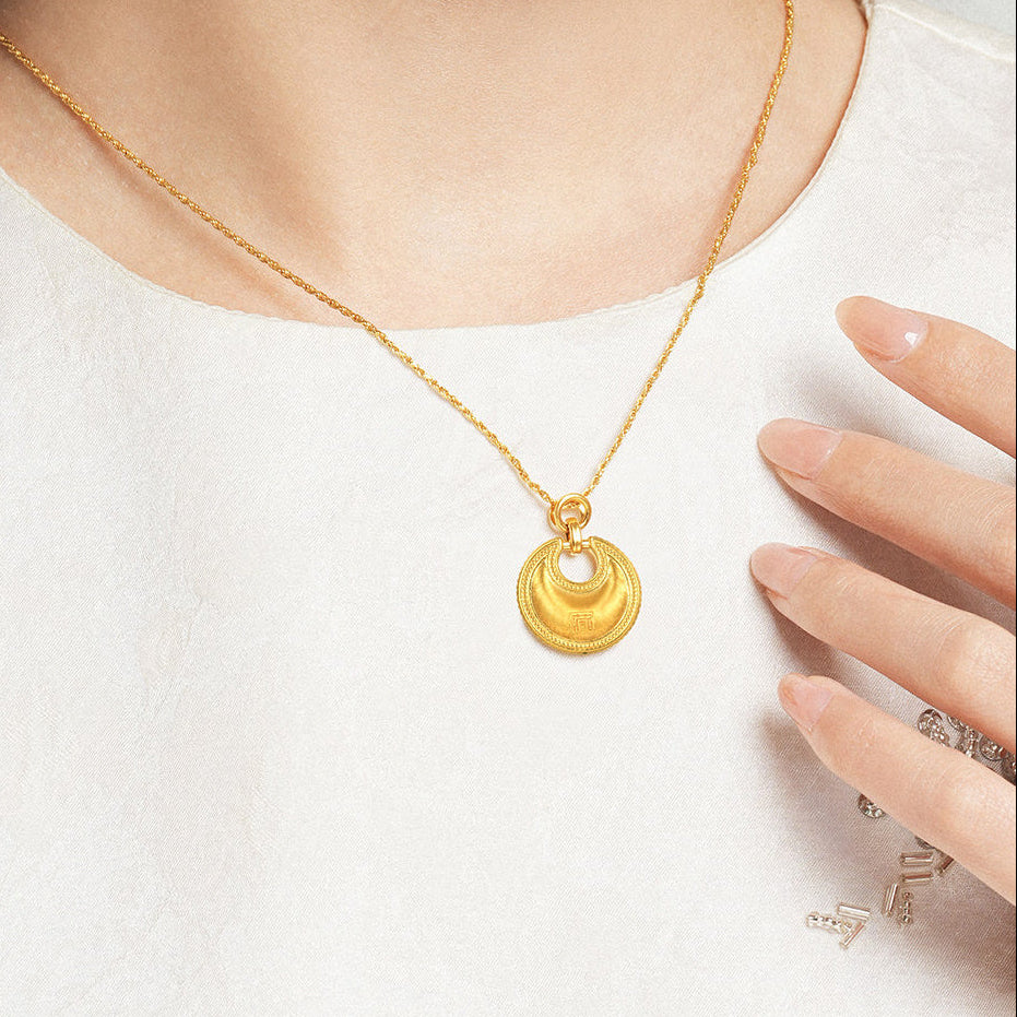Model wearing ChowTaiSeng 24K Gold Round Ruyi Lock Pendant on gold chain, white top, hand touching pendant, elegant lifestyle shot