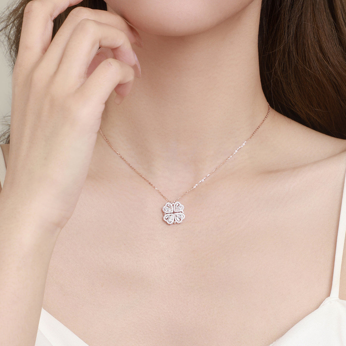 Model wearing a sparkling four-leaf clover necklace with heart-shaped cubic zirconia sections