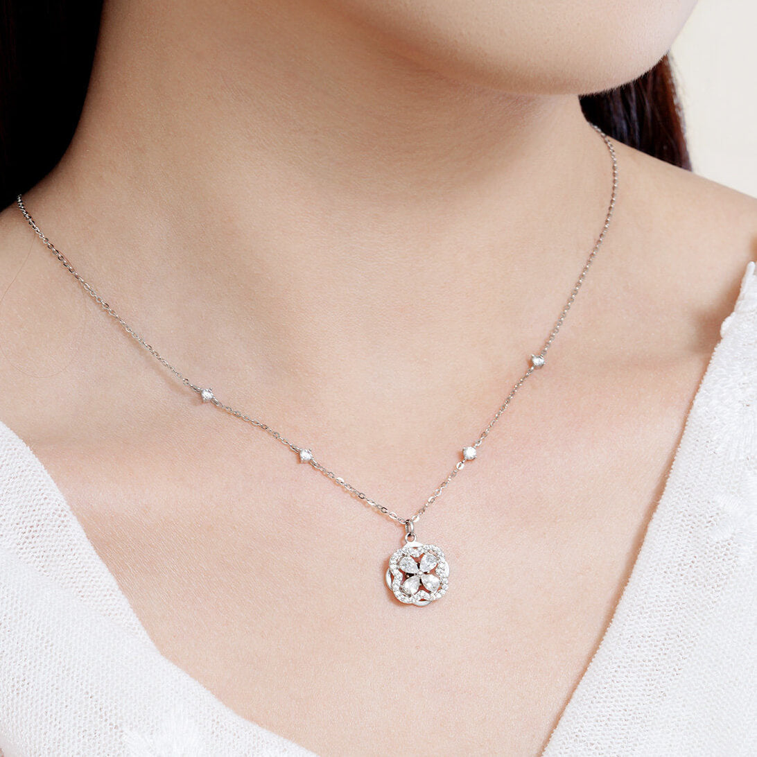 Close-up of a model wearing a silver-color cubic zirconia clover necklace with sparkling chain stations