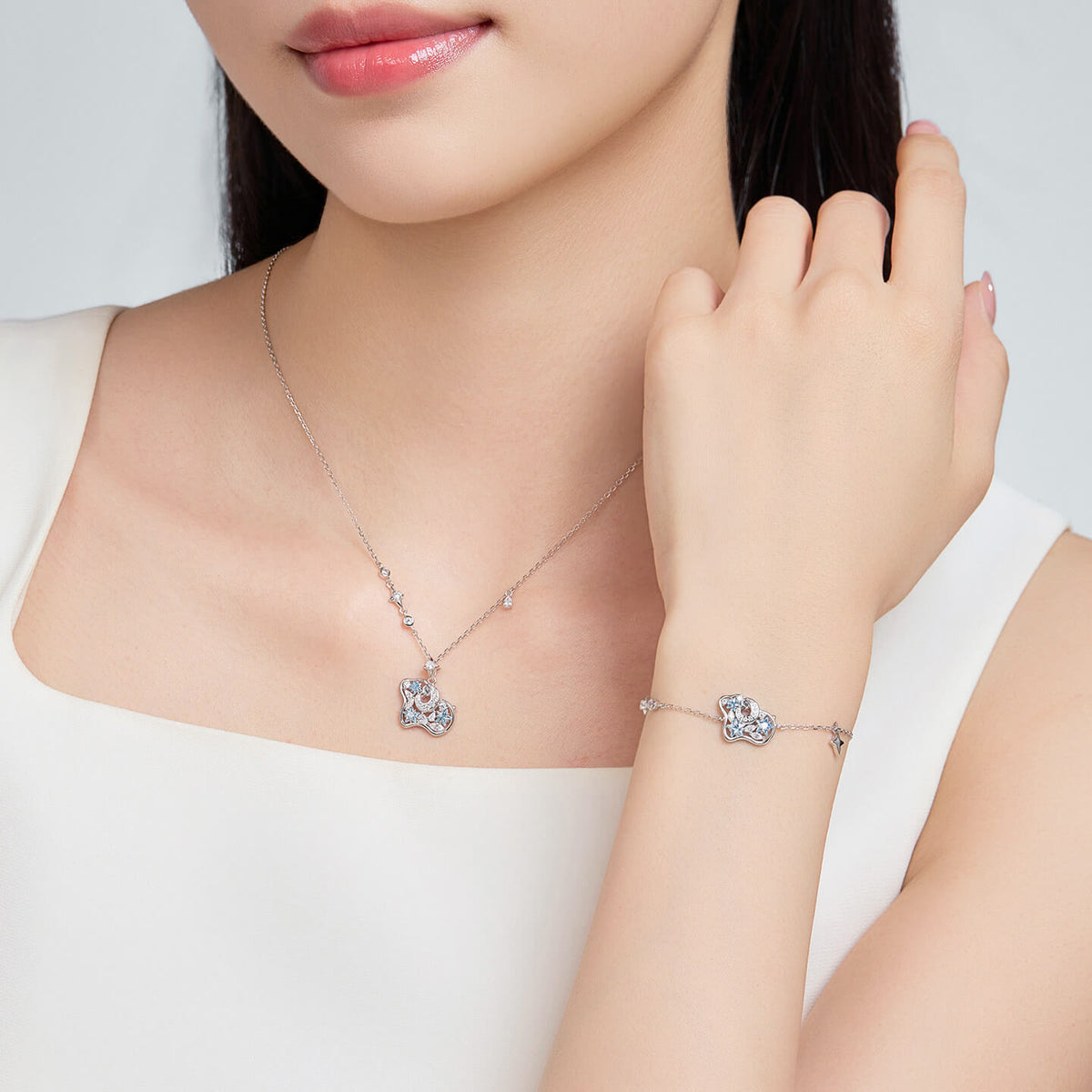 Model wearing a silver-tone blue cubic zirconia sheep necklace and matching bracelet with a white top