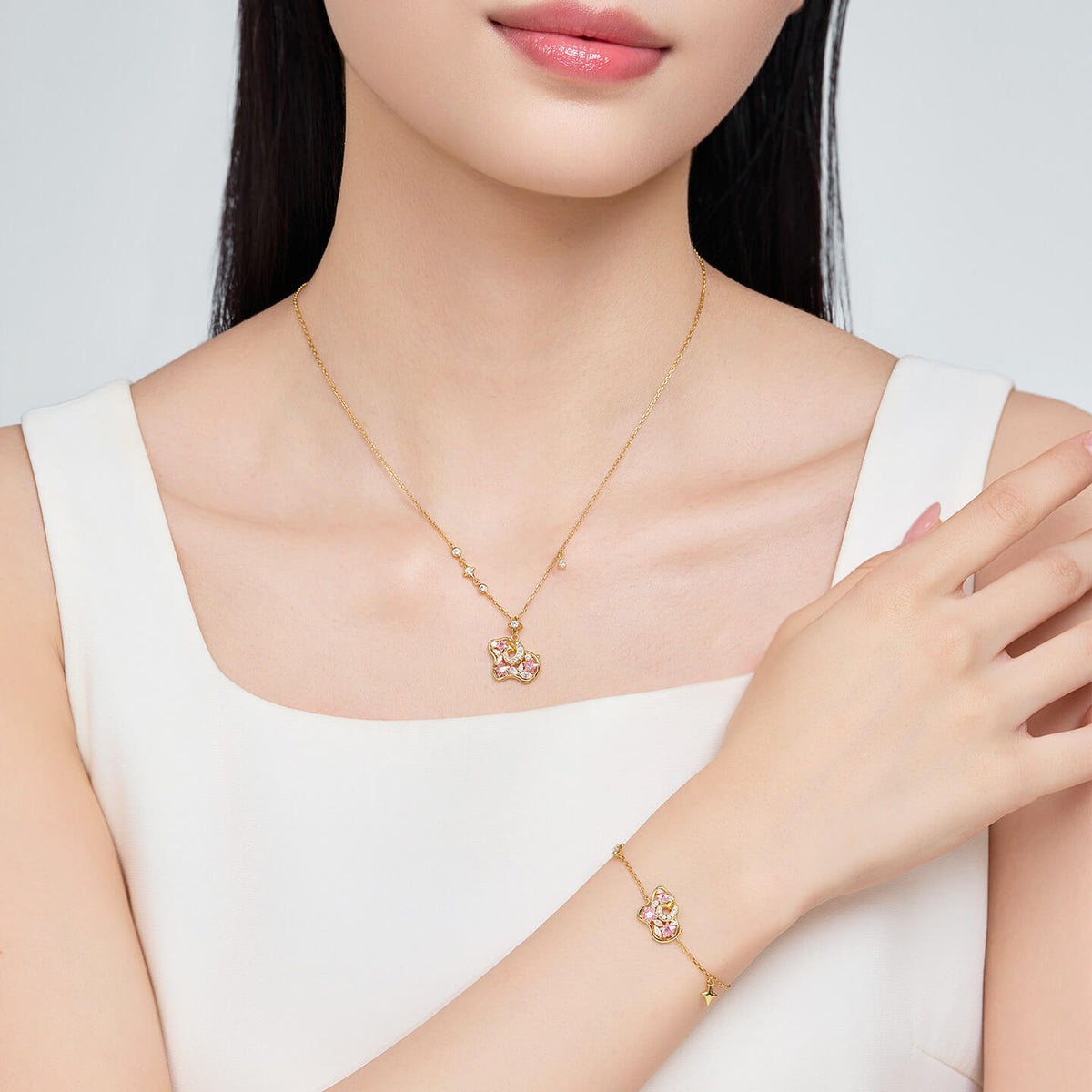 Model wearing a gold-tone pink cubic zirconia sheep necklace and matching bracelet with a white sleeveless top