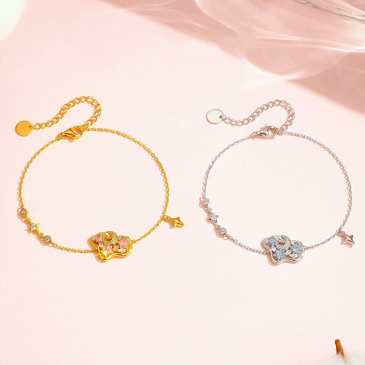 Gold-tone pink and silver-tone blue cubic zirconia sheep bracelets with star charms on a blush background