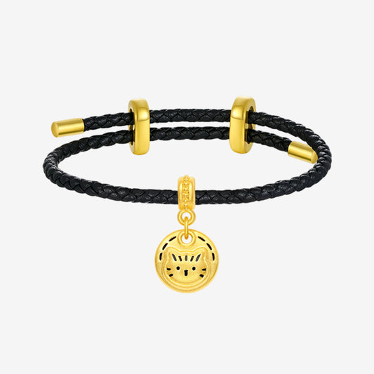 ChowTaiSeng 24K gold cat cookie round charm on black braided leather cord bracelet with gold ring spacers, white background