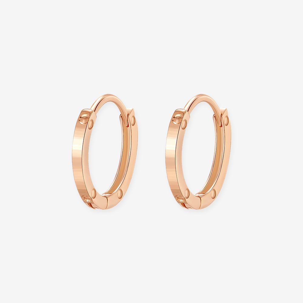 Pair of 18K rose gold huggie hoop earrings with polished surfaces and rivet-inspired circular details