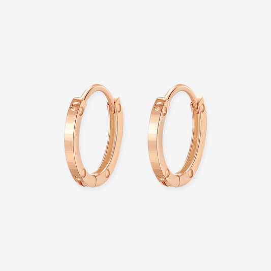 Pair of 18K rose gold huggie hoop earrings with polished surfaces and rivet-inspired circular details
