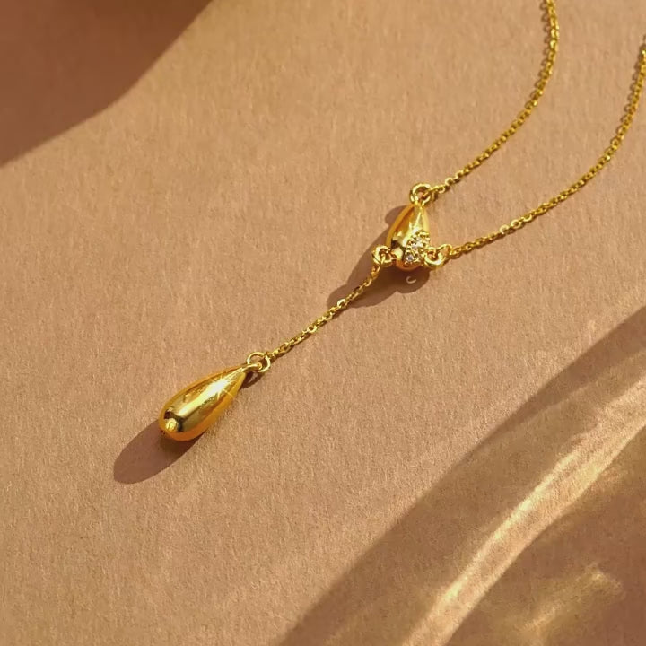 ChowTaiSeng 24K pure gold diamond teardrop Y lariat necklace in motion — dual teardrop Y-silhouette with diamond-inlaid upper drop and polished lower drop on delicate gold cable chain